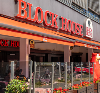 BLOCK HOUSE Berlin Am Alexanderplatz – Steakhouse mit Terrasse Außenansicht des BLOCK HOUSE Berlin Am Alexanderplatz mit Terrasse, Gästen an Tischen und Blick auf die Straße nahe dem Neptunbrunnen