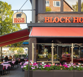 BLOCK HOUSE Hamburg Barmbek – Steakhouse mit Terrasse Außenansicht des BLOCK HOUSE Hamburg Barmbek mit Terrasse, roten Markisen und Sitzplätzen vor dem Steakhouse