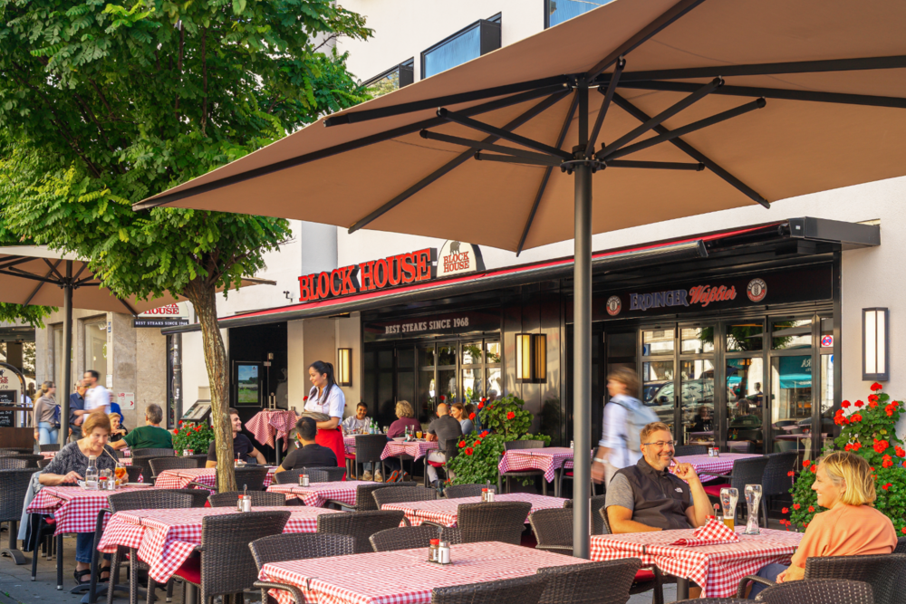 Terrasse des BLOCK HOUSE München am Rindermarkt mit Gästen und Servicekraft im Außenbereich.