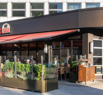 Außenansicht des BLOCK HOUSE Hannover am Thielenplatz mit Terrasse und Gästen im Außenbereich.