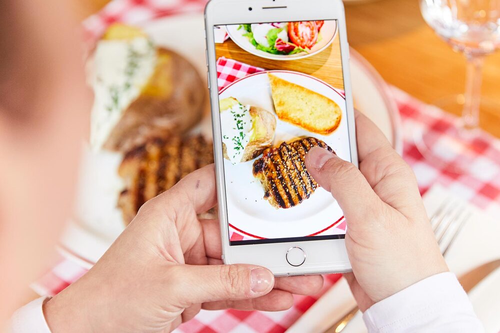 Eine Person fotografiert über das Handy einen Steakteller im BLOCK HOUSE