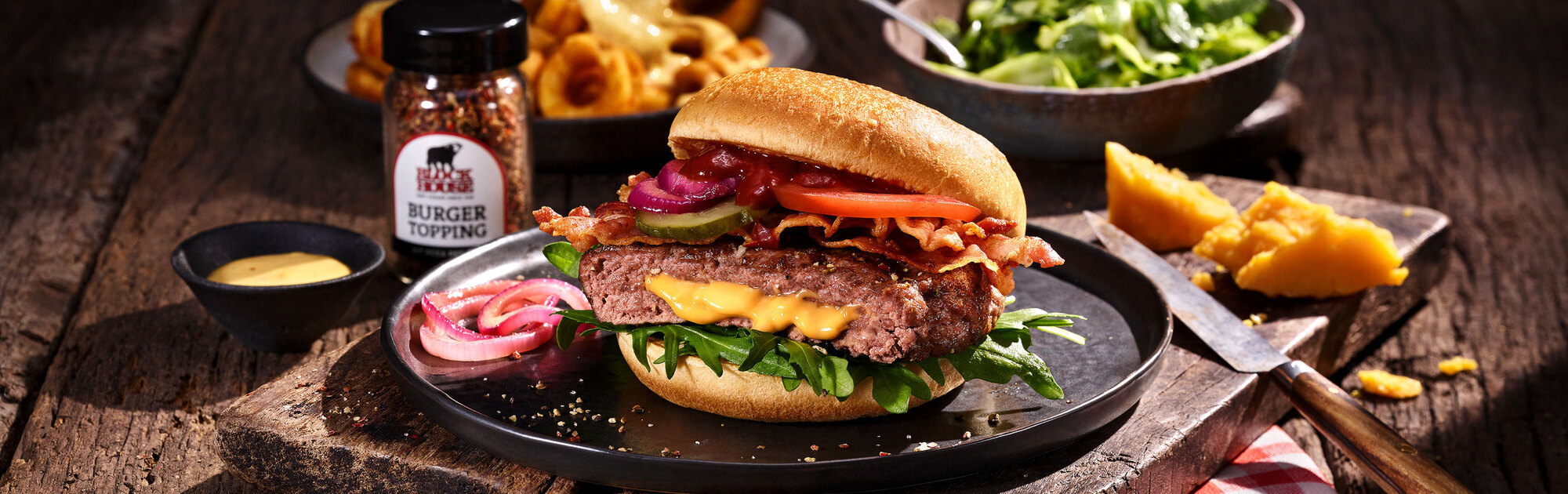 Der saftige BLOCK HOUSE Cheeseburger angerichtet auf einem Holzbrett