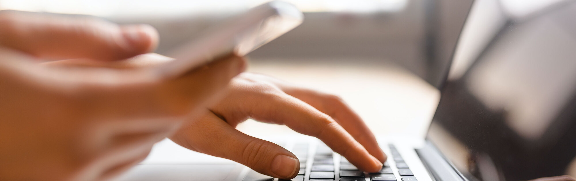 Person tippt auf der Tastatur eines Laptops