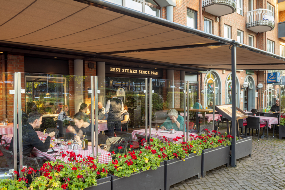 errasse vor dem BLOCK HOUSE Ahrensburg mit Gästen an Tischen mit rot-weiß karierten Tischdecken