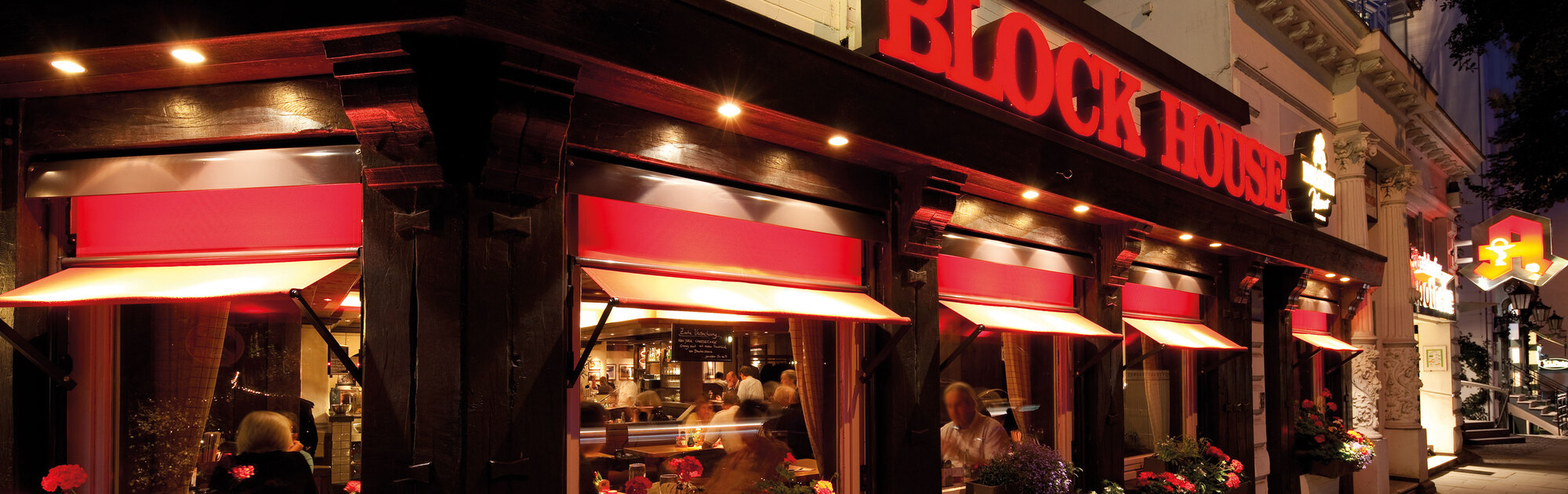 Blick durch das Fenster des BLOCK HOUSE Restaurant Pöseldorf in Hamburg auf essende Gäste