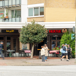 BLOCK HOUSE Hamburg Eppendorf Außenansicht des BLOCK HOUSE Hamburg-Eppendorf mit Terrasse und Passanten an der Straße.