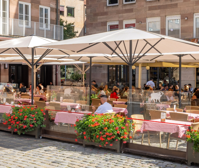 Speisende Gäste auf der sonnengeschützten Terrasse des BLOCK HOUSE Restaurants in Nürnberg