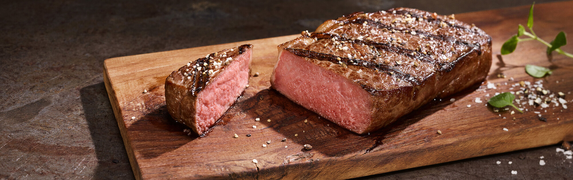 Saftig gegrilltes BLOCK HOUSE Steak liegt auf einem Holzbrett
