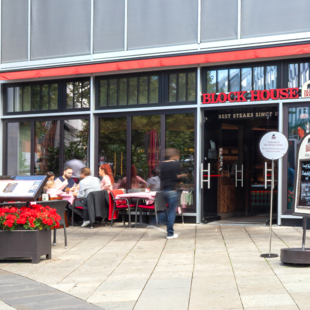 Außenansicht des BLOCK HOUSE Stuttgart Königstraße mit Terrasse und Gästen vor dem Restaurant.
