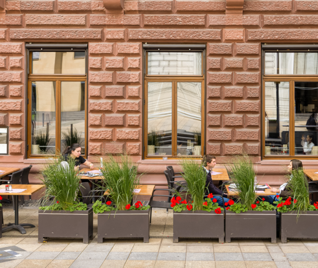 BLOCK HOUSE Frankfurt am Börsenplatz Außenansicht des BLOCK HOUSE Frankfurt am Börsenplatz mit Terrasse, begrüntem Außenbereich und Gästen vor dem Restaurant.