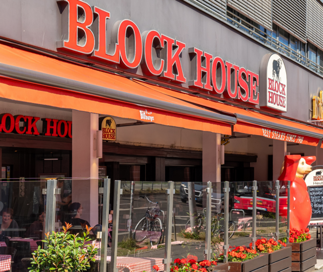 Außenansicht des BLOCK HOUSE Berlin Am Alexanderplatz mit Terrasse, Gästen an Tischen und Blick auf die Straße nahe dem Neptunbrunnen