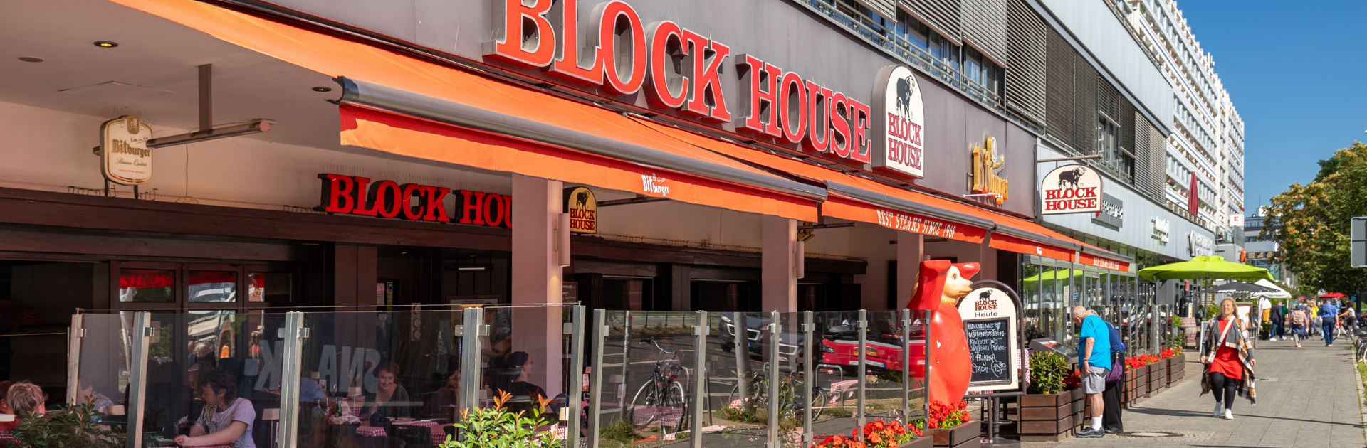 Außenansicht des BLOCK HOUSE Berlin Am Alexanderplatz mit Terrasse, Gästen an Tischen und Blick auf die Straße nahe dem Neptunbrunnen