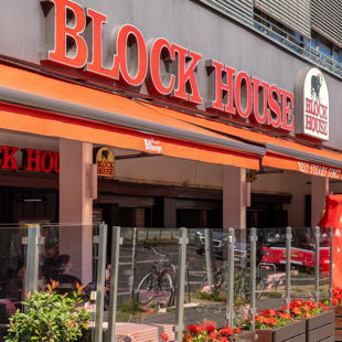 BLOCK HOUSE Berlin Am Alexanderplatz – Steakhouse mit Terrasse Außenansicht des BLOCK HOUSE Berlin Am Alexanderplatz mit Terrasse, Gästen an Tischen und Blick auf die Straße nahe dem Neptunbrunnen
