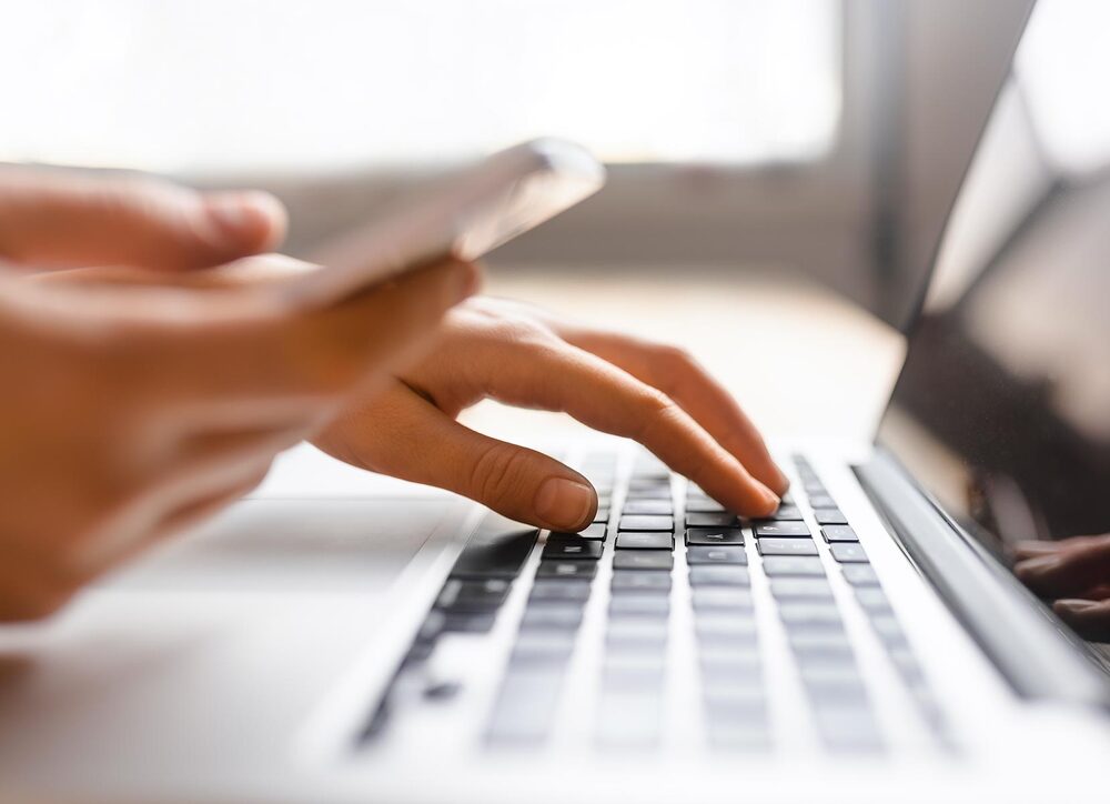 Person tippt auf der Tastatur eines Laptops