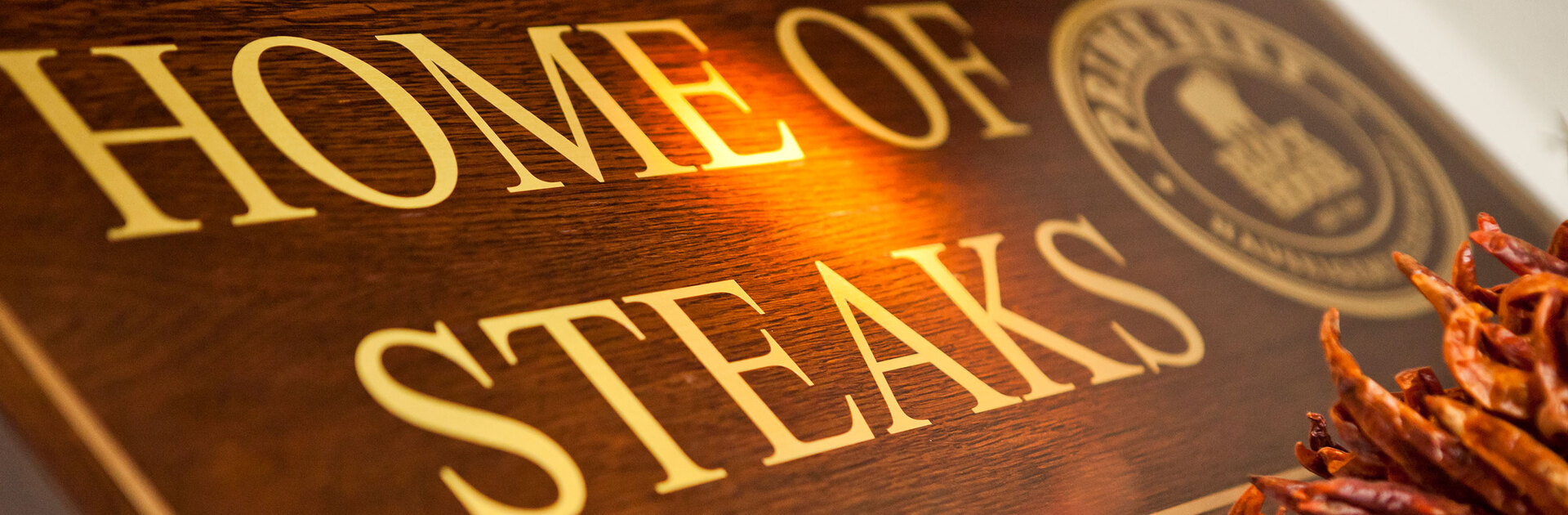 Blick von schräg unten auf ein Holzschild mit der Aufschrift "Home of Steaks"