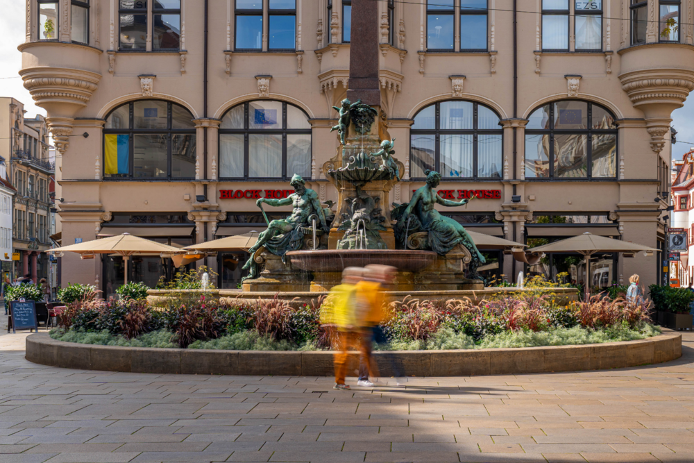 Außenansicht des BLOCK HOUSE Erfurt am Platz mit historischem Brunnen im Vordergrund.