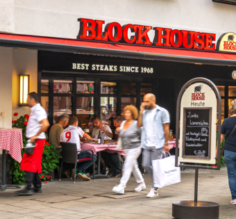 Außenansicht des BLOCK HOUSE München am Rindermarkt mit Gästen und Servicepersonal vor dem Restaurant.