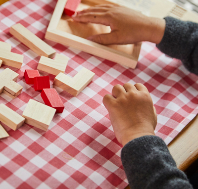 Kind sitzt am Tisch und spielt mit Puzzle aus Bauklötzen