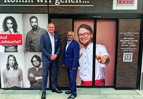 Zwei Herren in Anzügen stehen vor dem BLOCK HOUSE Restaurant München Rindermarkt mit Recruting-Werbung