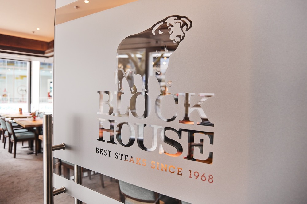 Glastür eines BlOCK HOUSE Restaurant mit der Aufschrift "BLOCK HOUSE" und dem Bullen.