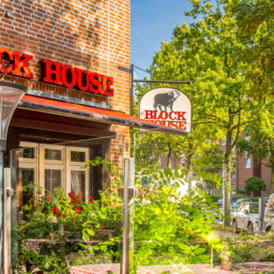 Terrasse vor dem BLOCK HOUSE Hamburg Eidelstedt mit Tischen und rot-weiß karierten Tischdecken vor dem Steakhouse